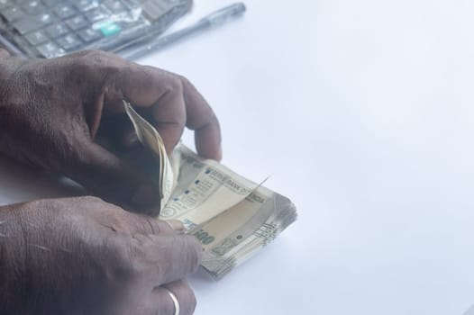 Senior aged Man hand counting Indian rupee note on table. High angle view. Close up.