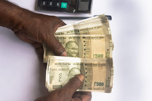 Business Man hand counting Indian rupee note on table. High angle view. Close up. White background.