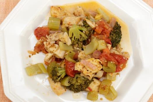 Close-up of ready-to-eat lunch of chicken meat with broccoli, carrots, onions, tomatoes and seasonings on an octagon plate. Cooked inner of lemon ginger chicken and mixed vegetable supper on a plate