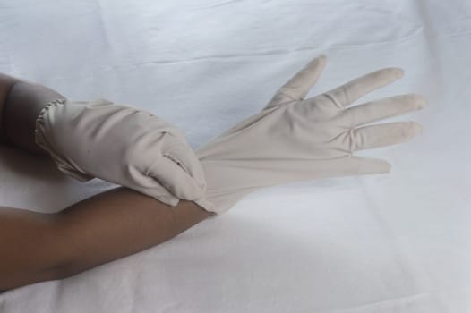 Hand Wearing Disposable Gloves against white background. High angle view. Close up. Use and protection of Hand Hygiene to reduce the risk of germs spreading due to hand contamination to environment.