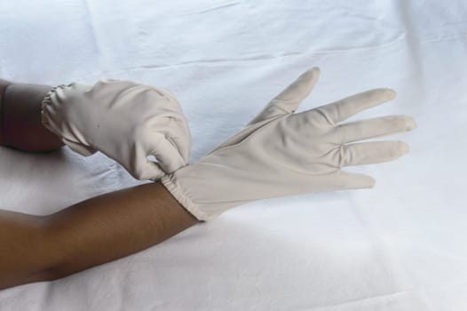Hand Wearing Disposable Gloves against white background. High angle view. Close up. Use and protection of Hand Hygiene to reduce the risk of germs spreading due to hand contamination to environment.