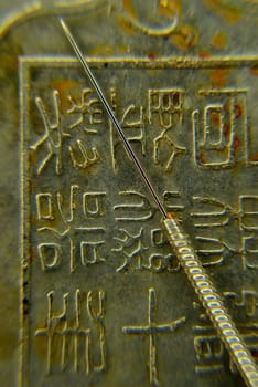 acupuncture needle on antique Chinese coin