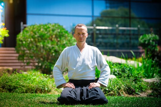 Young serious man aikido master in traditional costume