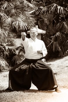 Young serious man aikido master in traditional costume