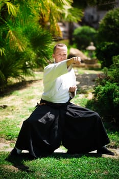 Young serious man aikido master in traditional costume