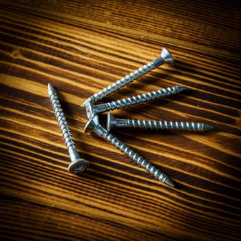 Closeup shot of a row of screws laid on a wooden table