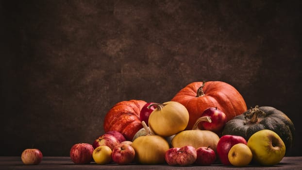 Thanksgiving background. Festive still life with pumpkins and apples on dark brown background with copy space. Happy Thanksgiving  day, autumn harvest or Halloween.