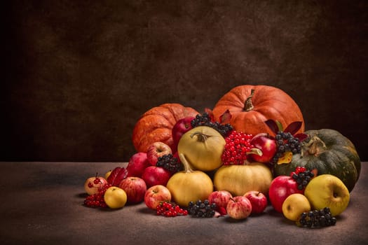 Thanksgiving background. Festive still life with pumpkins, berries, autumn leaves and apples on dark brown background with copy space. Happy Thanksgiving  day, autumn harvest, Halloween.