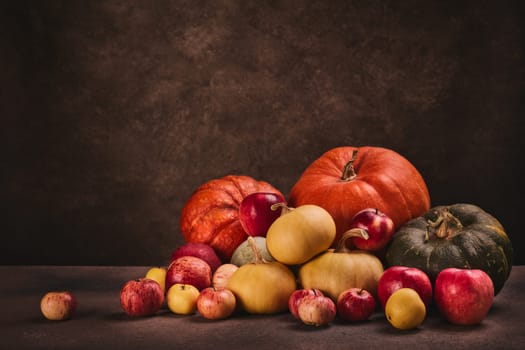 Thanksgiving background. Festive still life with pumpkins and apples on dark brown background with copy space. Happy Thanksgiving  day, autumn harvest or Halloween.