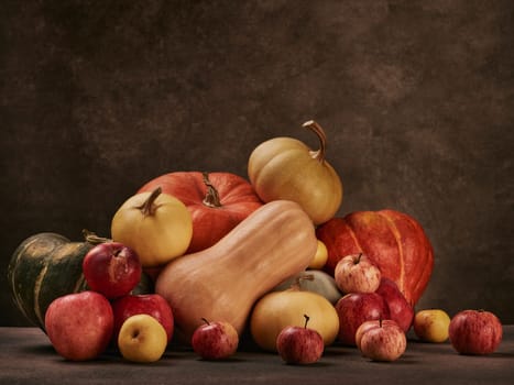 Thanksgiving background. Festive still life with pumpkins and apples on dark brown background with copy space. Happy Thanksgiving  day, autumn harvest or Halloween.