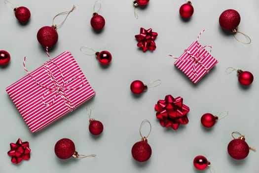 Gray background with two pink Christmas gift box presents, small red Christmas balls or sphere toys, ribbon bows for fir tree. Concept for festive sales, promotions, greeting card or invitation photo