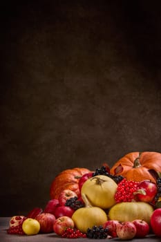 Thanksgiving background. Festive still life with pumpkins, berries, autumn leaves and apples on dark brown background with copy space. Happy Thanksgiving  day, autumn harvest, Halloween.