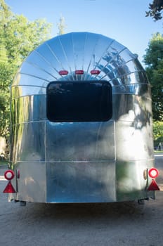 Rounded metal american caravan used as mobile catering vehicle. Rear view