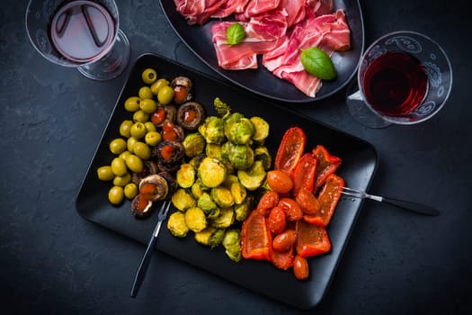 Assortment of appetizers and tapas with red wine on black background