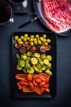Assortment of appetizers and tapas with red wine on black background