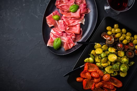 Assortment of appetizers and tapas with red wine on black background