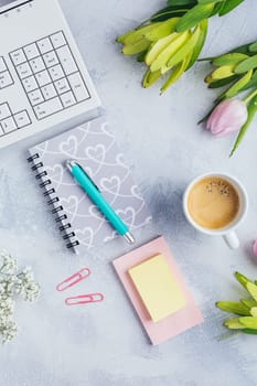 Workplace with cup of coffee, empty notebook, keyboard, supplies and flowers in bright tone