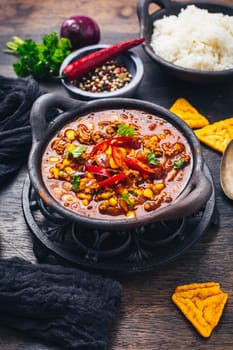 Bowl of chili con carne with rice and toppings on wooden table