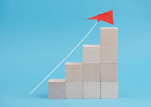 White line with an red airplane as an arrow going up, wooden cubes, blue background