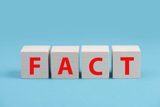 The word fact is standing in red letters on wooden cubes, blue colored background