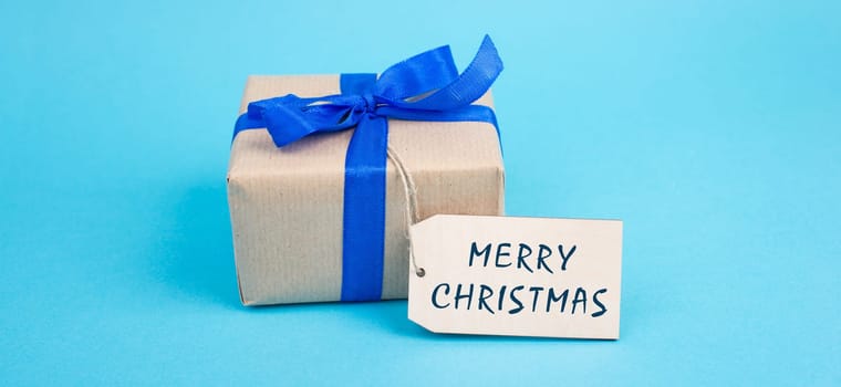 Gift box with a blue ribbon, tag with merry christmas, copy space