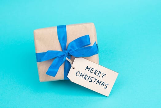 Gift box with a blue ribbon, tag with merry christmas, copy space