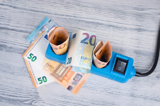 Euro banknotes in a power outlet, rising prices, expensive green electricity, Germany