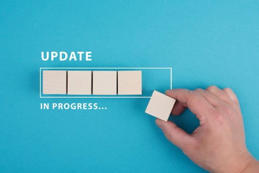The words update in progress are standing beside the loading bar, hand puts last cube to the upload, blue colored background