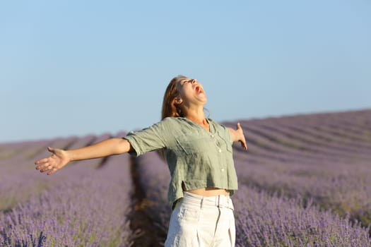 Happy woman screaming to the sky and spreading in a lavender field