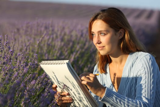 Happy woman drawing on notebook in a lavender field