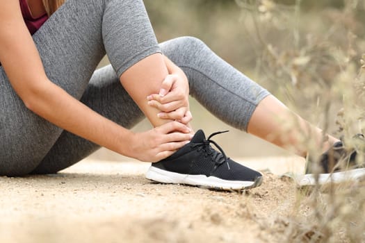 Close up of a runner suffering ankle lesion after sport in the mountain