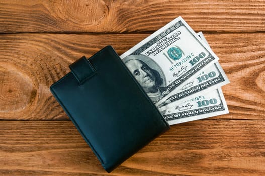 Dollars. A roll of hundred-dollar bills and scattered gold coins lying on the bills on a blue background with a side. Blue style.