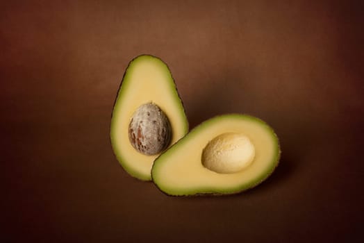 Halves of fresh avocado on a dark background. The concept of vegetarian nutrition.