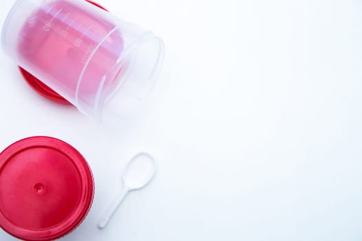 Jars for collecting tests with a red lid and a spoon on a white background. . High quality photo