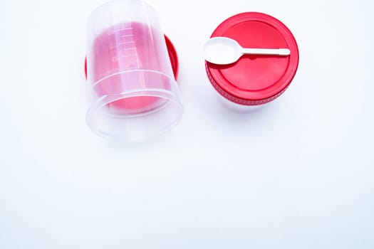 Jars for collecting tests with a red lid and a spoon on a white background. . High quality photo