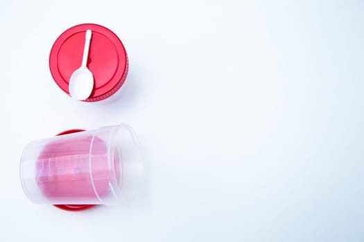 Jars for collecting tests with a red lid and a spoon on a white background. . High quality photo