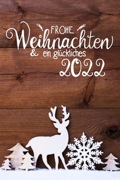 German Calligraphy Frohe Weihnachten Und Ein Glueckliches 2022 Means Merry Christmas And Happy 2022. Christmas Decoration Like Snowflake, Tree And Deer. Brown Wooden Background