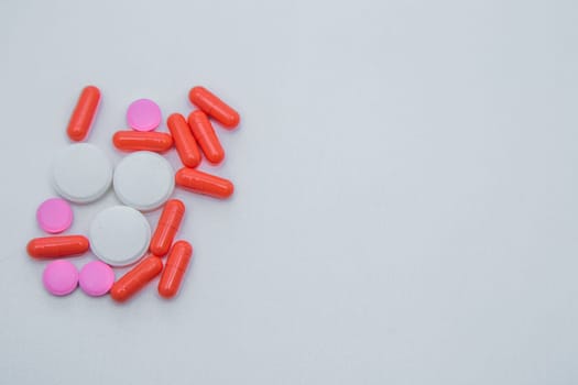 Tablets and capsules of white and pink color lie on the side on a white background. High quality photo