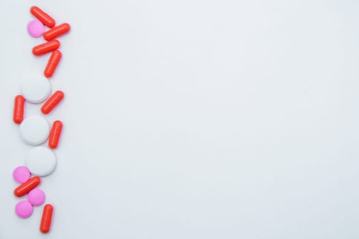 Tablets and capsules of white and pink color lie on the side on a white background. High quality photo