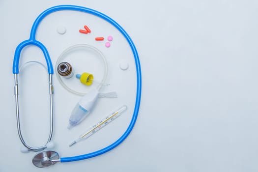 The stethoscope lies on a white background around, inside it is a baby aspirator, nose drops and pills.High quality photo