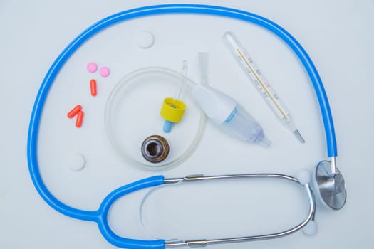 The stethoscope lies on a white background around, inside it is a baby aspirator, nose drops and pills.High quality photo