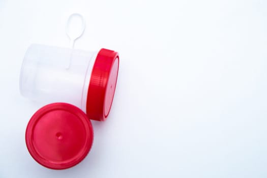 Jars for collecting tests with a red lid and a spoon on a white background. . High quality photo