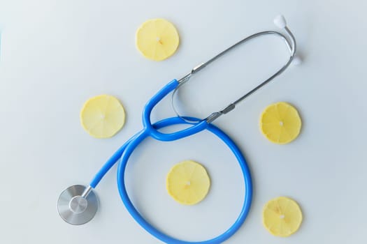 The blue stethoscope lies on a white background surrounded by lemon slices. High quality photo
