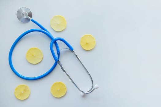 The blue stethoscope lies on a white background surrounded by lemon slices. High quality photo