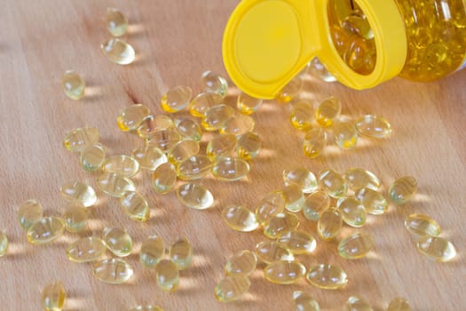 Fish oil omega pills spilled from an apothecary plastic bottle.
