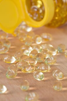 Fish oil omega pills spilled from an apothecary plastic bottle.