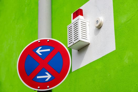 Fire alert light and no parking sign on a green house facade