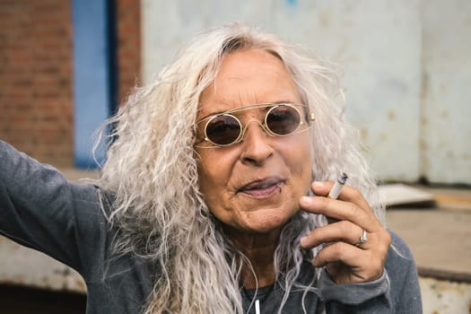 Beautiful woman with long bright curly hair is smoking a cigarette.