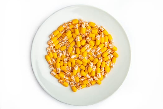 Yellow capsules on a white plate isolated on white background