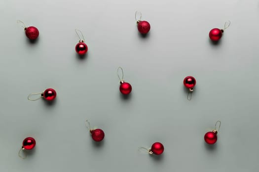 Pattern on gray background with small red Christmas balls or sphere toys for fir tree. Concept for festive minimalistic greeting card or invitation for Christmas eve celebration. High quality photo